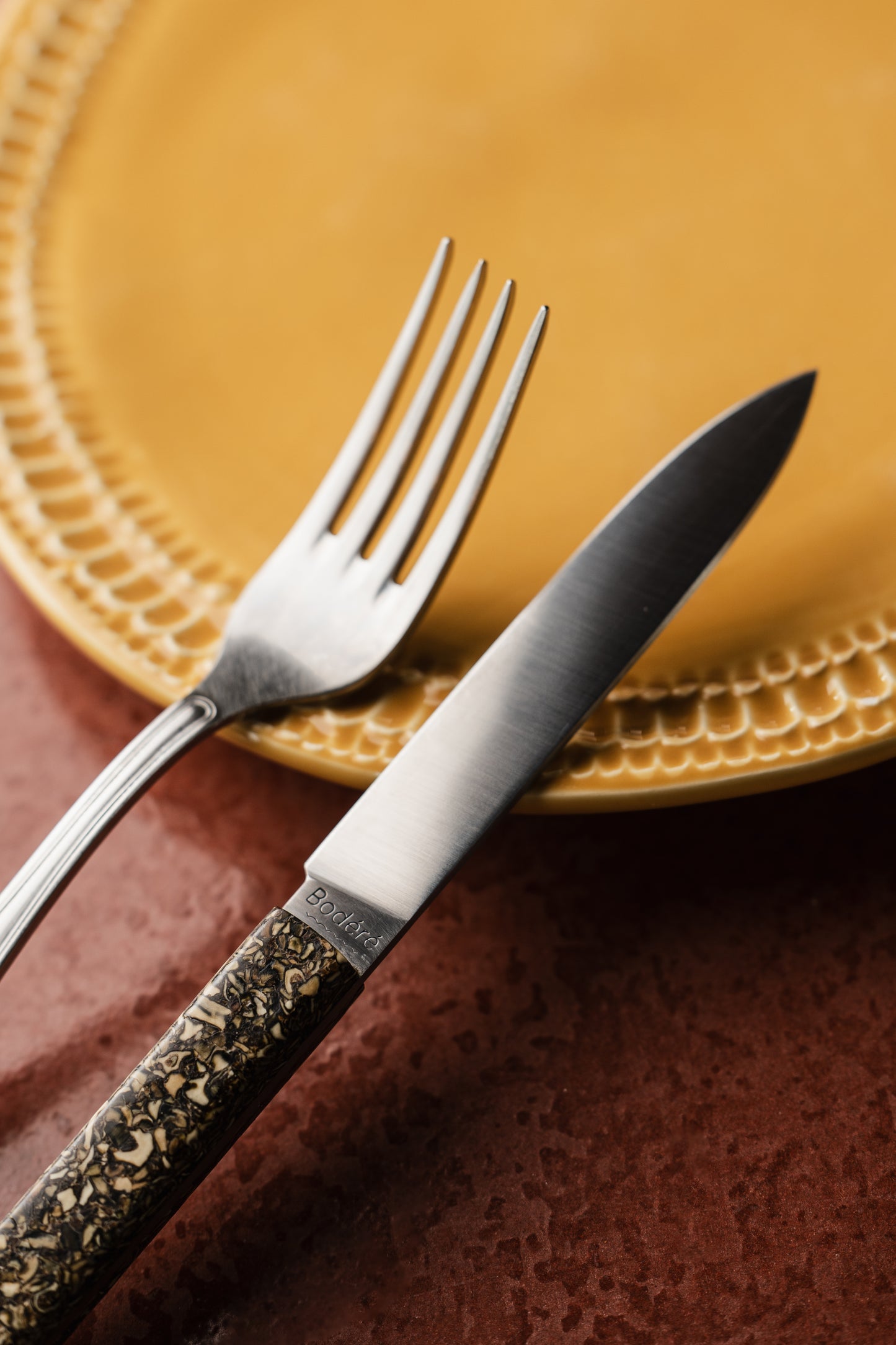 Les couteaux de table artisnaaux et durables de la coutellerie Bodéré mis en situation sur une table de salle à manger élégante et colorée.
